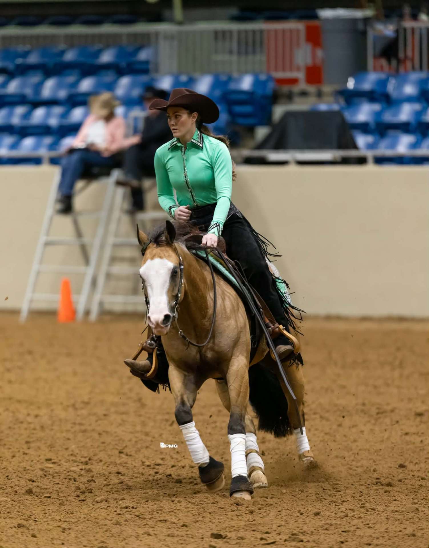 Carlene Langridge showing a buckskin Quarter Horse in a reining pattern